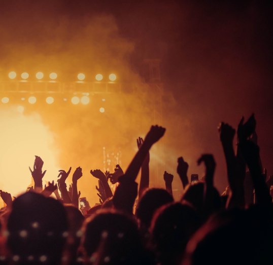 Crowd with raised hands in front of a lit main stage