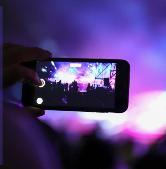 Phone filming a concert stage through festival bokeh